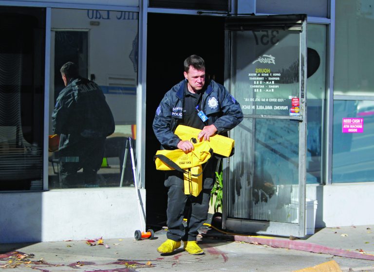 A police officer removes equipment at Fero's Bar and Grill in Denver on Wednesday, Oct. 17, 2012, where the bodies of a man and four woman were discovered after firefighters extinguished a fire at the bar early Wednesday morning. Police think the blaze was set to cover up their slayings. (AP Photo/Ed Andrieski)