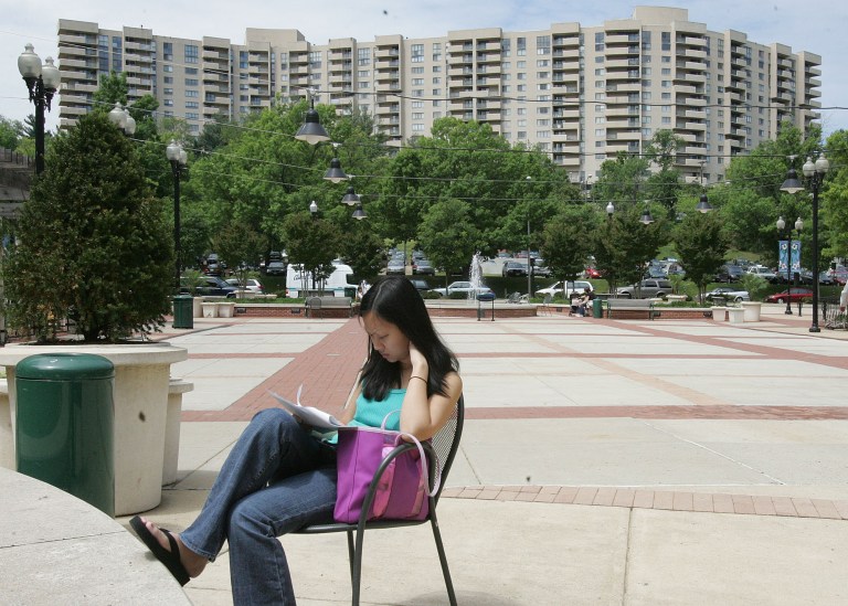 Published: No Published Caption
FILE - Theresa Nguyen, a pharmacy student studies on a Pentagon Row plaza, surrounded on three side by restaurants, shops, and apartments on the northwest quadrant of Pentagon City, Arlington Virginia, April 09 2006. Brig Cabe/Examiner    