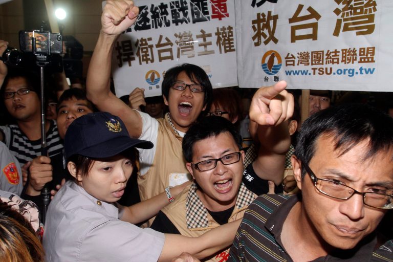 Protesters shout slogans as Zhang Zhijun, minister of Beijing's Taiwan Affairs Office, arrived at airport in Taoyuan county, Taiwan, Wednesday, June 25, 2014. China has sent Zhang, its first ever ministerial-level official to Taiwan for four days of meetings to rebuild ties with the self-ruled island that Beijing claims as its own, after mass protests in Taipei set back relations earlier this year. (AP Photo/Chiang Ying-ying)