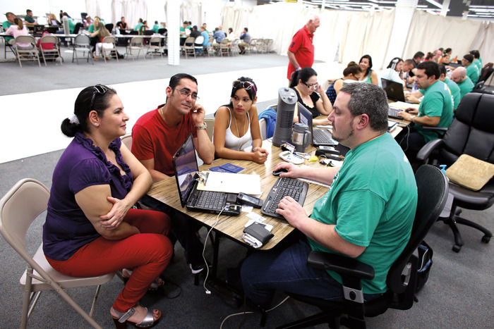 Yudelmy Cataneda, Javier Suarez and Claudia Suarez sit with Yosmay Valdivian, an insurance agent from Sunshine Life and Health Advisors as they and others try to purchase health insurance under the Affordable Care Act at a store setup in the Mall of Americas in Miami, Fla. (Joe Raedle/Getty Images)