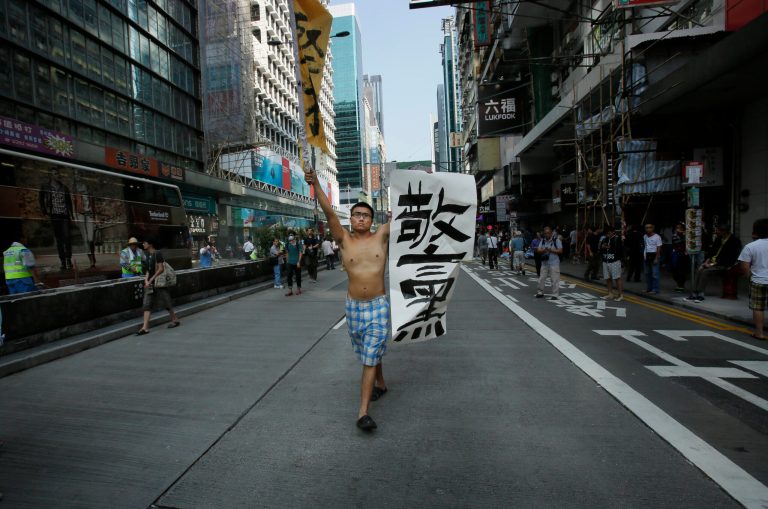 A pro-democracy protester carries a banner that reads: 