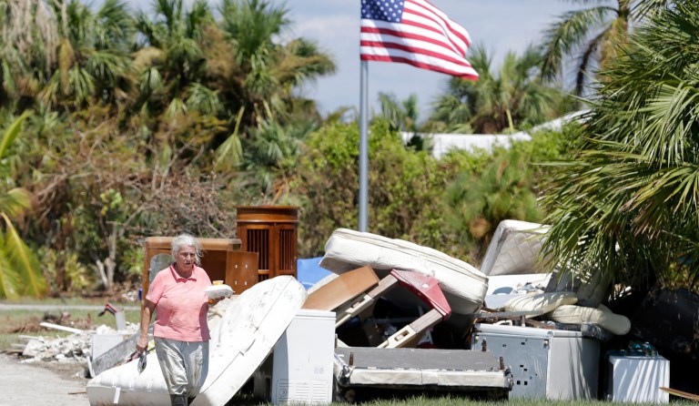 A woman walks by a pile of debris caused by storm surge during Hurricane Irma, Monday, Sept.18, 2017, in Everglades City, Fla. (AP Photo/Alan Diaz)