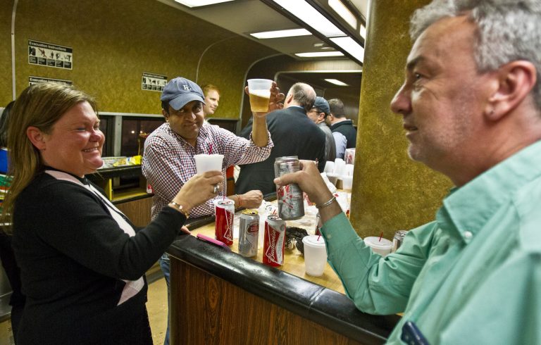 Nan Buziak Lexow, left, Srikanth Reddy, center, and Mark DeMonte, right, raise a toast while riding the bar car on the 7:07 p.m. train from Grand Central Terminal in New York to New Haven, Conn., Thursday, May 8, 2014.  The trio toasted the bar car, being retired from Metro-North's New Haven Line after Friday's afternoon rush hour.  The cars were a fixture on Metro-North Railroad trains for at least a half century. The cars, decked out with orange walls and faux wood paneling, are being retired Friday, because they cannot be coupled to the new fleet of train cars on the New Haven line. (AP Photo/Michael R. Sisak)