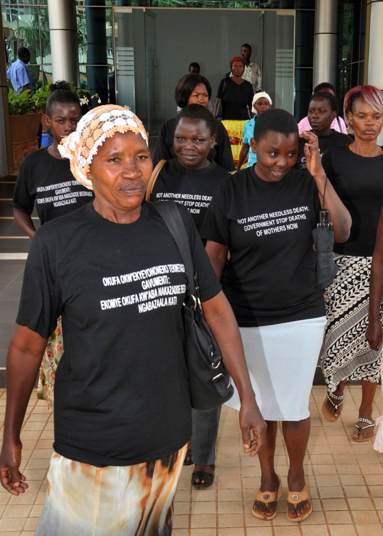   In this photo taken Tuesday, June 5, 2012, Ugandan women walk out of the Constitutional Court disappointed after losing a case against the government over maternal deaths during childbirth, prior to taking the issue further to the Supreme Court, in the capital Kampala, Uganda. More than 100 women die during childbirth each week in Uganda, a heartbreaking statistic that has energized activists to go to the Supreme Court in a bid to force the government to put more resources toward maternal health care to prevent the wave of deaths. Writing on t-shirts in English and Swahili reads 