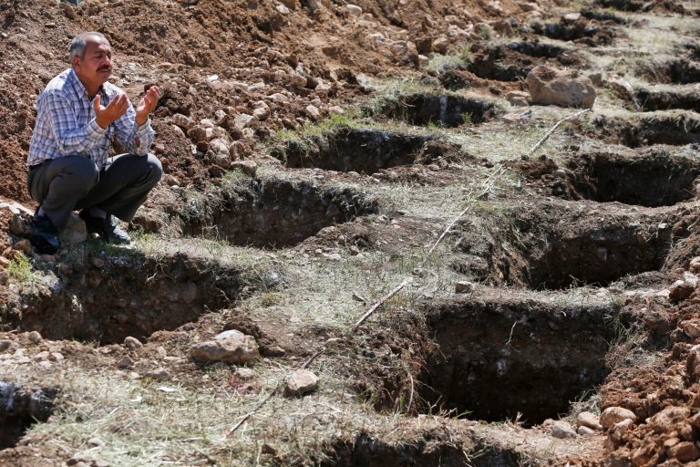 A man offers his prayers for the victims of the mining accident being buried during their funeral procession as he sits by empty graves prepared for the victims, in Soma, Turkey, Thursday, May 15, 2014. An explosion and fire at a coal mine in Soma, some 250 kilometers (155 miles) south of Istanbul, killed hundreds of workers, authorities said, in one of the worst mining disasters in Turkish history. (AP Photo/Lefteris Pitarakis)