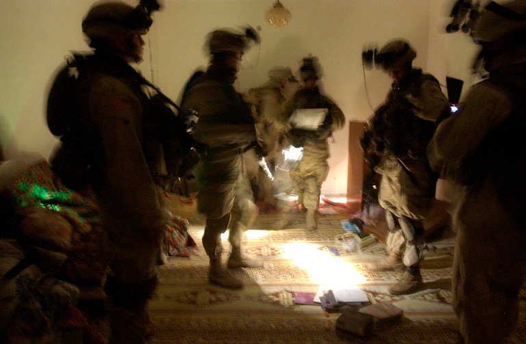  In this Wednesday, Jan. 14, 2004 file photo, soldiers with the 82nd Airborne Division spread out documents and other objects on the floor while looking for evidence during a raid on an Iraqi house near Fallujah, Iraq. (AP/Julie Jacobson)
