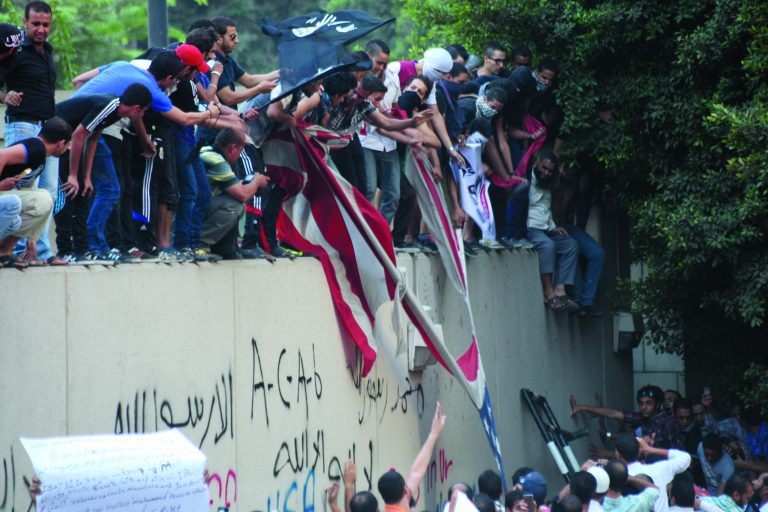 Protesters destroy an American flag pulled down from the U.S. embassy in Cairo, Egypt, Tuesday, Sept. 11, 2012. Egyptian protesters, largely ultra conservative Islamists, have climbed the walls of the U.S. embassy in Cairo, went into the courtyard and brought down the flag, replacing it with a black flag with Islamic inscription, in protest of a film deemed offensive of Islam. (AP Photo/Mohammed Abu Zaid)