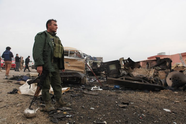 A member of the Kurdish forces stands in an area damaged by an improvised explosive device placed by Islamic State militants that killed several Peshmerga fighters and injured dozens, Thursday, Dec. 18, 2014. (AP Photo/Zana Ahmed)