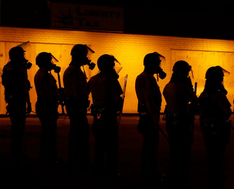 FILE - In this Sunday, Aug. 17, 2014, file photo, police wait to advance after tear gas was used to disperse a crowd during a protest for Michael Brown, who was killed by a police officer on Aug. 9, in Ferguson, Mo. The national legal standards that govern when police officers are justified using force against people trace their lineage to a 1984 case from Charlotte, N.C. Brown's shooting has prompted multiple investigations and triggered days of rioting reflecting long-simmering racial tensions in a town of mostly black residents and a majority white police force.  (AP Photo/Charlie Riedel, File)