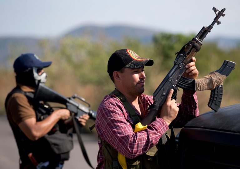 FILE - In this Jan. 14, 2014 file photo, armed men belonging to the Self-Defense Council of Michoacan, (CAM), stand guard at a checkpoint at the entrance of Antunez, Mexico. The government announced that it had reached a deal with vigilante leaders to incorporate the armed civilian groups into old and largely forgotten quasi-military units called the Rural Defense Corps. Vigilante leaders met Tuesday Jan. 28, with government officials to hash out details of the agreement. (AP Photo/Eduardo Verdugo, file)