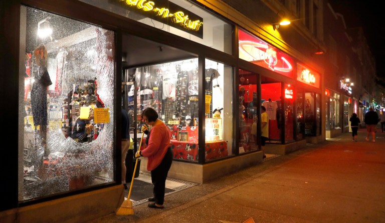 Lori Shifter helps clean up after a violent crowd broke windows after clashing with police Sunday, Sept. 17, 2017, in University City, Mo. Earlier, protesters marched peacefully in response to a not guilty verdict in the trial of former St. Louis police officer Jason Stockley. (AP Photo/Jeff Roberson)