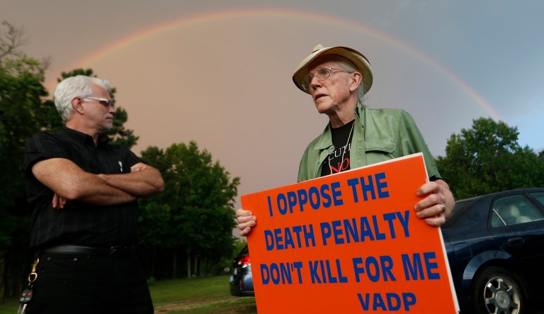 Dale Brumfield, field Director for Virginians for Alternatives to the Death Penalty, left, and Jack Payden-Travers, right stand under a rainbow as the Greensville Correctional Center Thursday, July 6, 2017, in Jarratt, Va. The two arrived for a vigil in opposition to the execution of William Morva who is scheduled to receive a lethal injection on Thursday for the 2006 killings of a hospital security guard and sheriff's deputy. (AP Photo/Steve Helber)