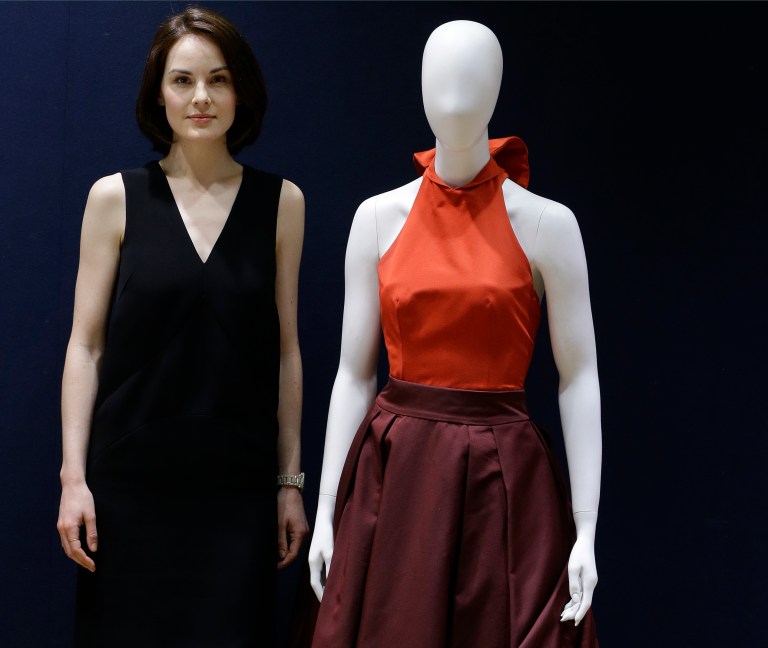 RECROP OF LKW106 In this Wednesday, May 14, 2014 photo, British actress Michelle Dockery, stands with her Prada gown that she wore to the 2013 Emmy's, at Christie's auction rooms in London. 