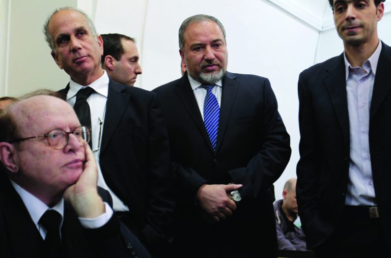 Israel's former hard-line Foreign Minister Avigdor Lieberman, second right, is seen with lawyers and aides as he arrives at a Jerusalem court for the opening hearing of his trial on charges of fraud and breach of trust, Sunday, Feb. 17, 2013. Lieberman is accused of trying to advance the career of a former diplomat who relayed information to him about a since-closed criminal investigation into his business dealings. (AP Photo/Ariel Schalit)