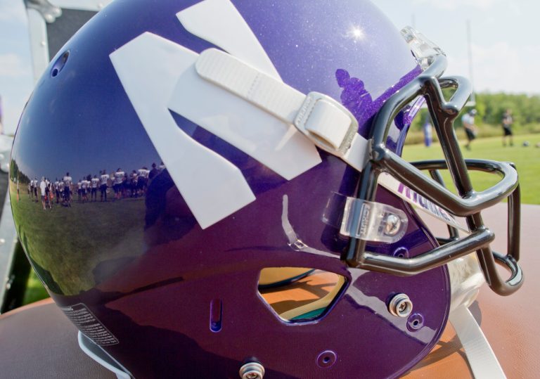 Northwestern football players are reflected in a helmet during drills at practice at the University of Wisconsin-Parkside campus on Monday, Aug. 17, 2015, in Kenosha, Wi. (AP Photo/Jeffrey Phelps)