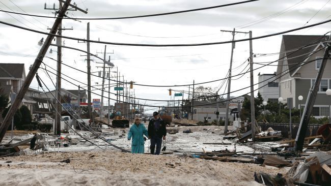 In this Wednesday, Oct. 31, 2012 file photo, Robert Bryce, right, walks with his wife, Marcia Bryce, past downed utility poles and other debris from Superstorm Sandy on Route 35 in Seaside Heights, N.J. AP Photo