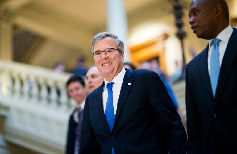 In this March 19, 2015, photo, former Florida Gov. Jeb Bush, left, walks with former campaign staff member Rufus Montgomery, right, while visiting the Georgia Capitol in Atlanta.(AP Photo/David Goldman)