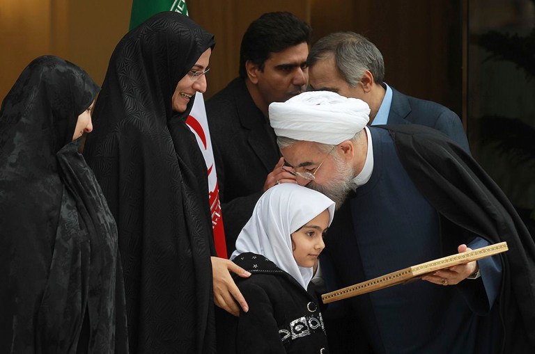 In this photo released by the official website of the office of the Iranian Presidency, Iran's President Hassan Rouhani kisses the head of Armita, daughter of Iranian scientific researcher Darioush Rezaeinejad who was assassinated in July 2011, during a news briefing after Iran and world powers came to an agreement in Geneva over its nuclear program, at the Presidency compound in Tehran, Iran, Sunday, Nov. 24, 2013. Iran struck a historic deal Sunday with the United States and five other world powers, agreeing to a temporary freeze of its nuclear program in the most significant agreement between Washington and Tehran in more than three decades of estrangement. (AP Photo/Presidency Office, Mohammad Berno)