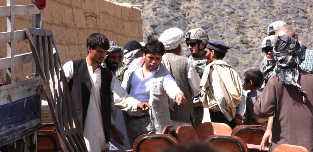 A local contractor from an Afghan construction and supply company counts desks with villagers in the Kohi Sofi district of Afghanistan's Parwan province as Task Force Gladiator soldiers distribute school supplies in 2008. (Photo: U.S. Army)
