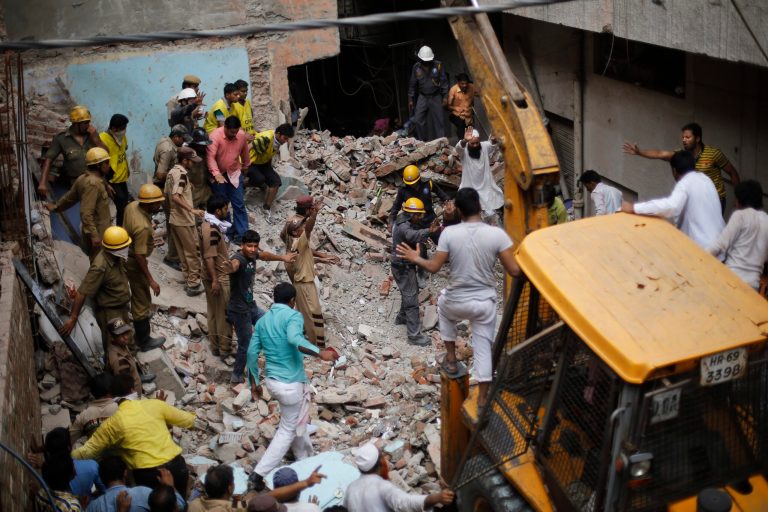 Indian rescuers gesture for an excavator to stop as they try to retrieve the body of a victim at the site of a building collapse in New Delhi, India, Saturday, June 28, 2014. A dilapidated building collapsed in the Indian capital on Saturday, killing at least seven people as rescuers searched for others believed to be trapped. (AP Photo/Altaf Qadri)