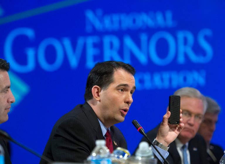 Wisconsin Gov. Scott Walker uses a cell phone to illustrate a point about health care plans during a special session on jobs in America during the National Governor's Association Winter Meeting in Washington, Sunday, Feb. 23, 2014. (AP Photo/Cliff Owen)