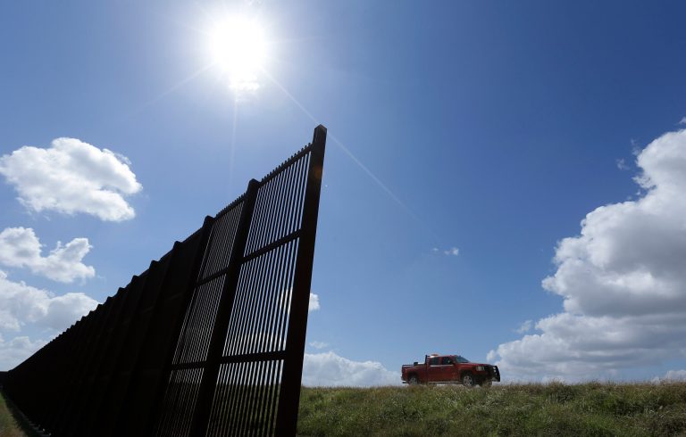 A Texas man drives his truck along the border fence in Brownsville, Texas. (AP image)
