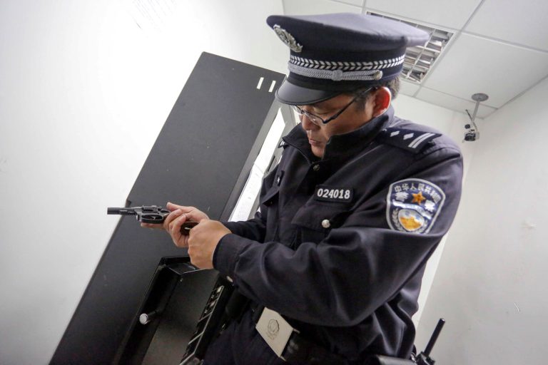 FILE - In this April 20, 2014 file photo, a Chinese policeman checks his pistol before going on patrol in Shanghai, China. By arming its patrolling officers, China has abandoned its decades-old policy of unarmed local police in response to concerns over crime and terrorism, leaving Britain, Norway and New Zealand among the major countries where regular patrolling police still generally do not carry arms. (AP Photo, File) CHINA OUT