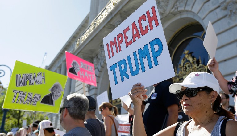 People hold up signs at a rally calling for the impeachment of President Trump. A new poll shows, 70 percent of Democrats believe Congress should move to impeach Trump and 7 percent of Republicans believe the same.(AP Photo/Jeff Chiu)