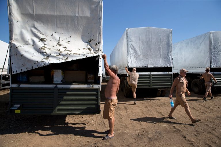 Drivers prepare to show cargos to journalists in a field where the aid convoy is parked in Voronezh, about 28 kilometers (17 miles) from Ukrainian border, Rostov-on-Don region, Russia, Friday, Aug. 15, 2014. The Ukrainian government threatened to use all means available to block the convoy if the Red Cross was not allowed to inspect the cargo. Such an inspection would ease concerns that Russia could use the aid shipment as cover for a military incursion in support of the separatists, who have come under growing pressure from government troops. (AP Photo/Pavel Golovkin)
