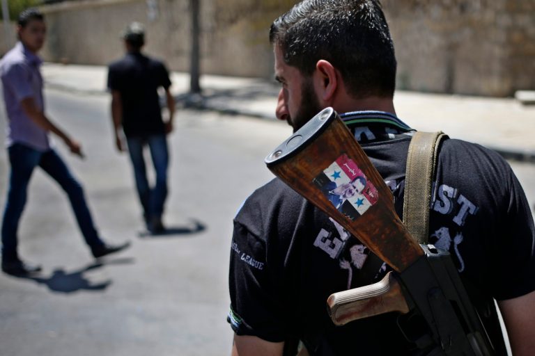 FILE - This Aug. 21, 2013 file photo shows a Syrian military soldier holding his AK-47 with a sticker of Syrian President Bashar Assad and Arabic that reads, 