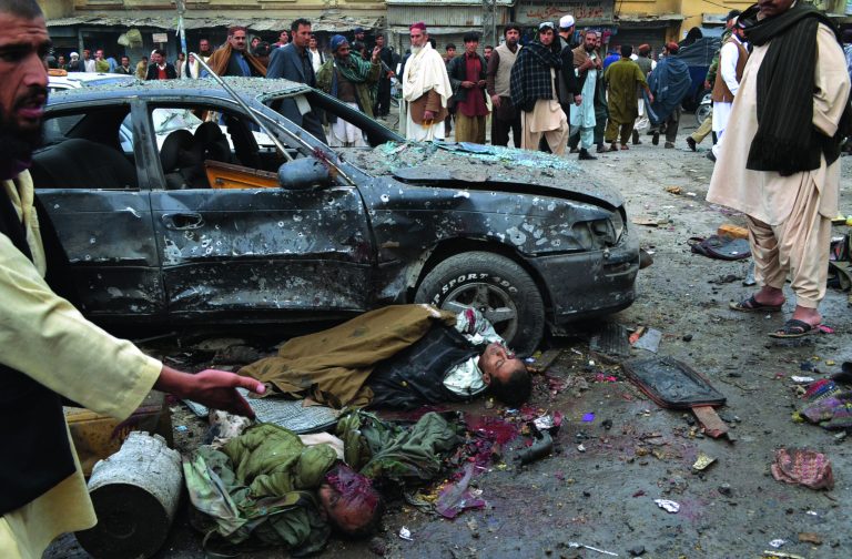 EDS NOTE: GRAPHIC CONTENT - The bodies of two dead men lie in the street at the site of a bomb blast that targeted paramilitary soldiers in a commercial area of Quetta, Pakistan, killing at least 12 people and wounding more than 40 others, according to police, Thursday, Jan. 10, 2013. A series of bombings in different parts of Pakistan killed 115 people on Thursday in one of the deadliest days in the country in recent years. (AP Photo/Arshad Butt)