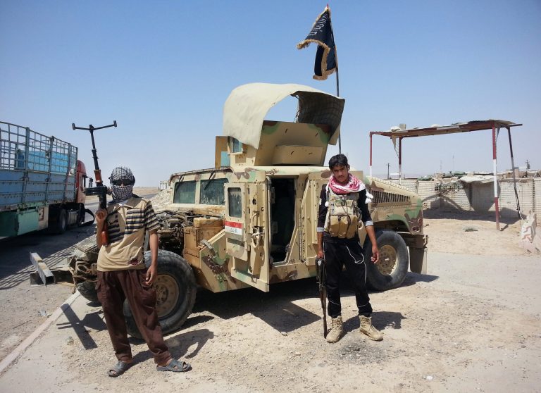 In this file photo taken Thursday, June 19, 2014, Islamic State group militants stand with a captured Iraqi army Humvee at a checkpoint outside Beiji refinery, some155 miles north of Baghdad, Iraq. (AP Photo, File)