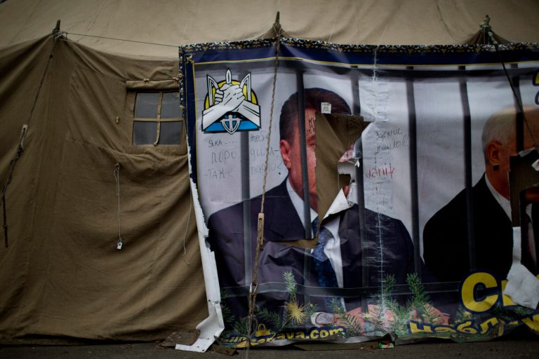 A torn poster of Ukrainian President Viktor Yanukovych, who fled the capital and went into hiding after months of protests against his government, is seen fixed on a tent set by protesters at Kiev's Independence Square, Wednesday, Feb. 26, 2014. (AP Photo/Emilio Morenatti)