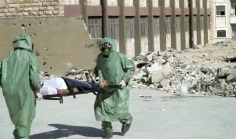 This image made from an AP video posted on Wednesday, Sept. 18, 2013 shows Syrians in protective suits and gas masks conduct a drill on how to treat casualties of a chemical weapons attack in Aleppo, Syria. (AP Photo via AP video)