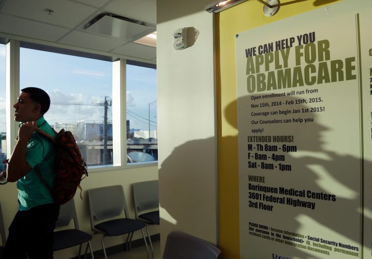 Giovanny Vega, 18, of Miami, walks past a sign with information on signing up for health insurance under the Affordable Care Act after signing up for health insurance at the Borinquen Medical Center, Monday, Nov. 17, 2014, in Miami. (AP Photo/Lynne Sladky)