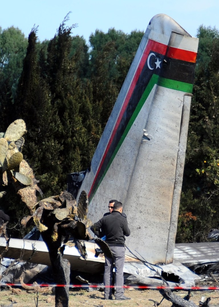 Tunisian investigators examine the site of a Libyan Antonov 26 aircraft that crashed near the village of Benyanou at 40 kilometers (25 miles) southeast of Tunis, the capital, Friday, Feb. 21, 2014. A medical flight from Libya crashed in a field near Tunis in the early hours of Friday morning, killing all 11 Libyans on board, Tunisia's civil defense said. (AP Photo/Hassene Dridi)