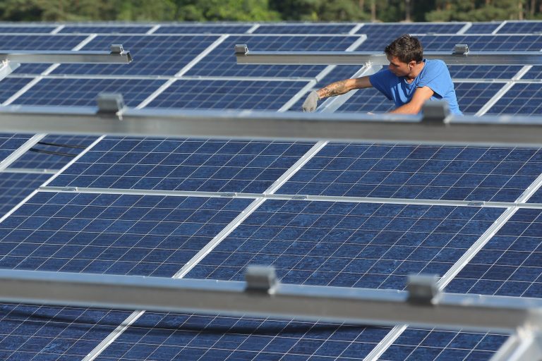 MUENCHEBERG, GERMANY - SEPTEMBER 04:  A worker installs solar panels containing photovoltaic cells at the new Solarpark Eggersdorf solar park on September 4, 2012 near Muencheberg, Germany. The park, which is being built by German solar energy operator juwi Solar GmbH, will contain 85,000 solar modules and is one of many similar projects in eastern Germany. Germany is investing heavily in renewable energy projects, especially solar, wind and biogas ventures, as the country is in the ongoing process of closing down its nuclear energy plants.  (Photo by Sean Gallup/Getty Images)