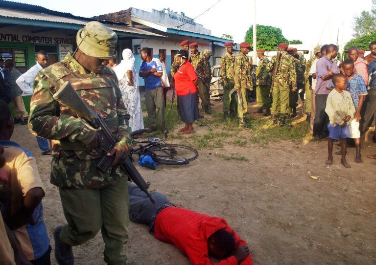 A member of the Kenyan security forces walks past the body of one of those who were killed by militants, in the village of Kibaoni just outside the town of Mpeketoni, about 100 kilometers (60 miles) from the Somali border on the coast of Kenya, Monday, June 16, 2014. Dozens of Somali extremists wielding automatic weapons attacked the small Kenyan coastal town for hours, assaulting the police station, setting two hotels on fire, and spraying bullets into the street killing dozens, officials said Monday. (AP Photo)
