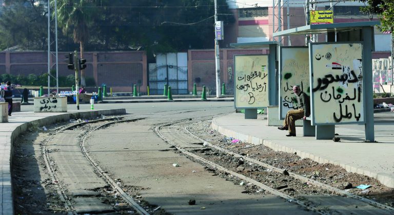 A man sits on a bench in front of the presidential palace in Cairo, Egypt, Thursday, Dec. 13, 2012. Egypt's opposition called on its followers to vote 