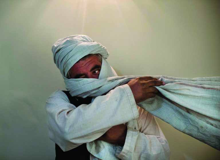 A Monday, Oct. 15, 2012 photo, shows a Taliban fighter from central Afghanistan who is known to the Associated Press from the time of Taliban rule in Afghanistan, but cannot be identified, is seen during an interview with the Associated Press wrapping a cloth around his face, in Kabul, Afghanistan. As the clock ticks toward 2014 and the final withdrawal of NATO and U.S. troops, peace talks with the Taliban are floundering even as the Taliban are showing some hopeful signs, attending international conferences and issuing a statement from their reclusive one-eyed leader with a surprise offer to share power in Afghanistan. (AP Photo/Anja Niedringhaus)