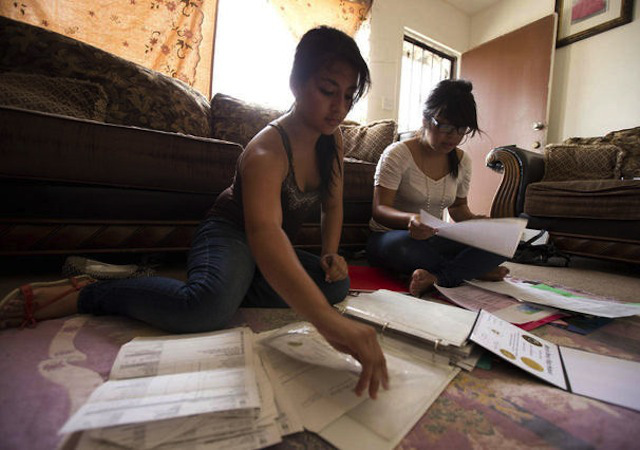 Itzel Guillen, left, sorts out some of the documents she needs to apply for the Deferred Action for Childhood Arrivals program, also known as DACA, with Lucero Maganda, right, at her home in San Diego, Ca. (AP Photo/Gregory Bull)