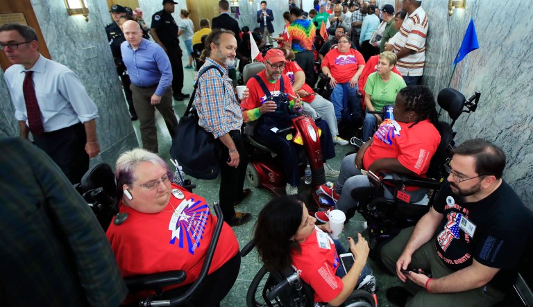 Marilee Adamski-Smith from Brookfield, Wis., left, and Colleen Flanagan of Boston, center, join others outside a hearing room where the Senate Finance Committee will hold a hearing to consider the Graham-Cassidy healthcare proposal, on Capitol Hill in Washington, Monday, Sept. 25, 2017. (AP Photo/Manuel Balce Ceneta)
