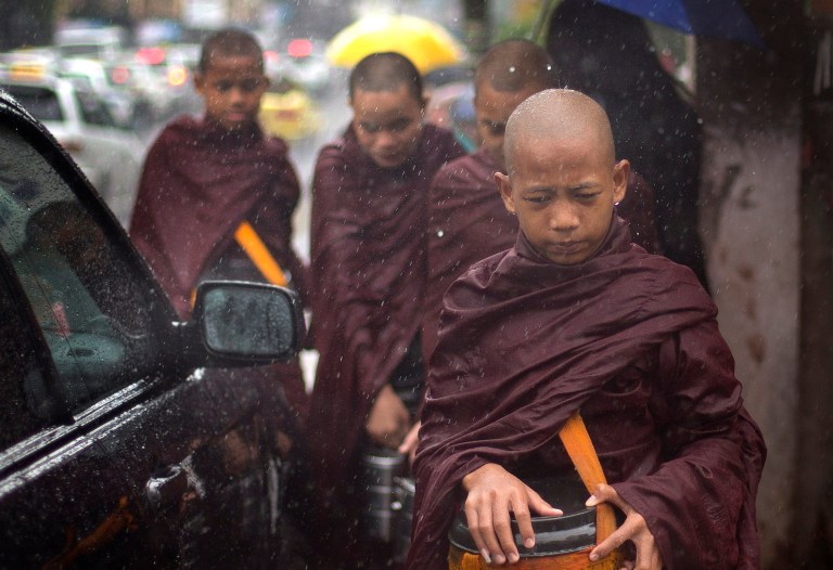 Novice Buddhist monks walk to collect alms in the rain following a cleric's rule of no footwear nor use of umbrellas on a street of Yangon, Myanmar, Thursday, July 31, 2014. Downpours during the monsoon season are intense, and often more than 100 millimeters (3.9 inches) of water falls in an hour resulting flash floods and traffic jams. (AP Photo/Gemunu Amarasinghe)