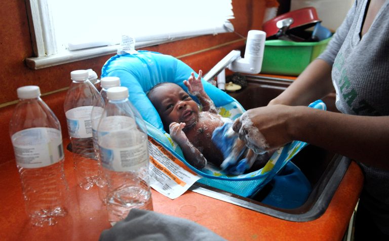 Porshe Loyd uses bottled water to wash her three-week-old son, LeAndrew, in a baby bather in the kitchen sink at their home in Flint, Mich., on Jan. 28, 2016. Improperly treated water leached lead from pipes into drinking water after Flint switched from Detroit's water system to the Flint River in 2014 to save money while under state financial management. (Todd McInturf/The Detroit News via AP)