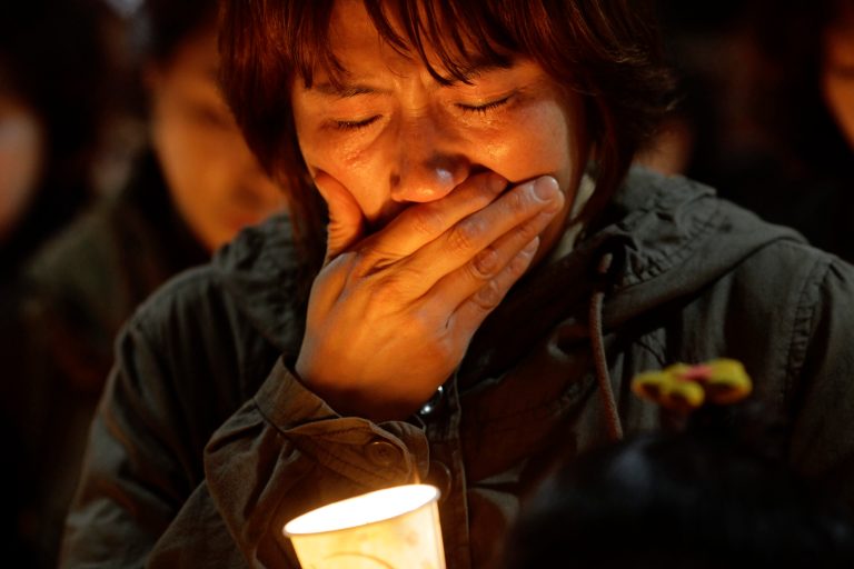 A woman offers prayers during a candlelight vigil for the missing passengers of a sunken ferry at Danwon High School in Ansan, South Korea, Thursday, April 17, 2014. An immediate evacuation order was not issued for the ferry that sank off South Korea's southern coast, likely with scores of people trapped inside, because officers on the bridge were trying to stabilize the vessel after it started to list amid confusion and chaos, a crew member said Thursday.  (AP Photo/Wonghae Cho)