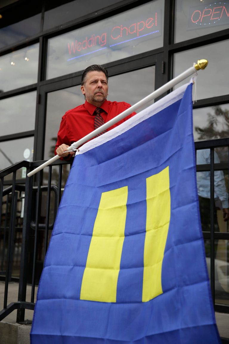 Logan Seven prepares to raise a an equality flag at the Chapelle de l'amore wedding chapel Tuesday, Oct. 7, 2014, in Las Vegas. The 9th U.S. Circuit Court of Appeals in San Francisco struck down the ban on same sex marriages in Nevada and Idaho on Tuesday. (AP Photo/John Locher)