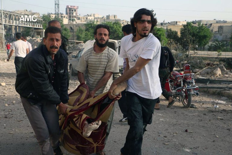 This Sunday, May 4, 2014 photo provided by the anti-government activist group Aleppo Media Center (AMC), which has been authenticated based on its contents and other AP reporting, shows Syrian men carrying the body of a man who was killed by a government forces airstrike, in Aleppo, Syria. Syrian state media say on Monday, May 5, 2014 rockets have slammed into a government-held district in the northern city of Aleppo, killing many people. (AP Photo/Aleppo Media Center AMC)
