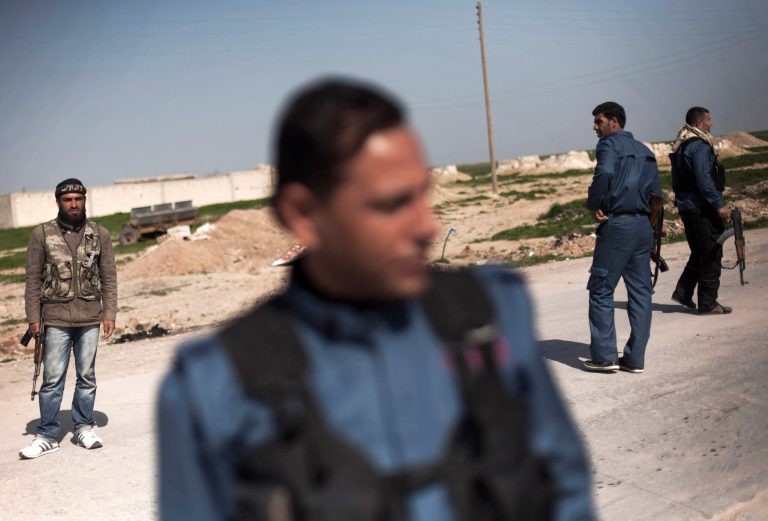 FILE - In this Wednesday, Feb. 27, 2013 file photo, members of the Kurdish Popular Protection Units and Free Syrian Army fighters stand guard at a check point at Ras al-Ayn, Syria. With Sunni extremist fighters on the offensive against Kurdish areas in northern Syria using modern weapons recently captured from Iraqi forces, the Kurds' civil administration is putting forward plans to impose compulsory military service on residents in order for them to take part in protecting their land. (AP Photo/Manu Brabo, File)
