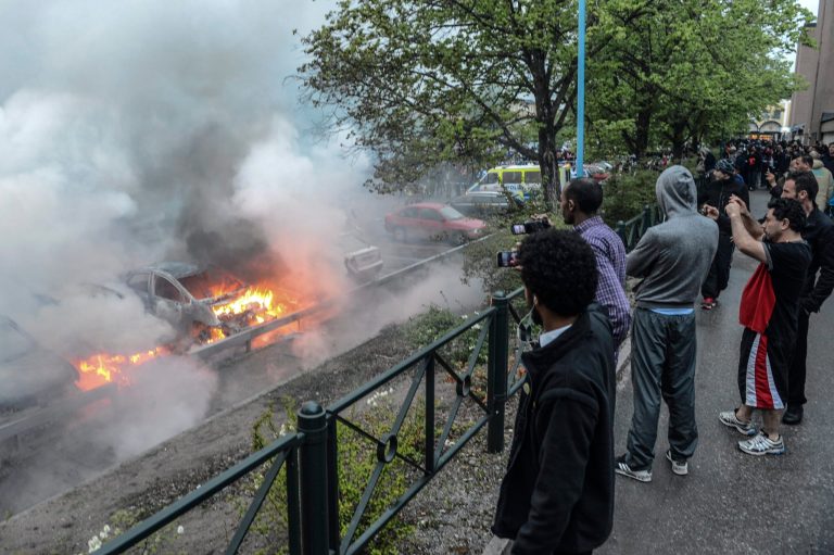 Bystanders take photos of a row of burning cars in the Stockholm suburb of Rinkeby after youths rioted in several different suburbs around Stockholm for a fourth consecutive night, late Thursday May 23, 2013. Youths in immigrant-heavy Stockholm suburbs torched cars and threw rocks at police in riots believed to be linked to a deadly police shooting of a local resident in the suburb of Husby. (AP Photo/Scanpix, Fredrik Sandberg) SWEDEN OUT