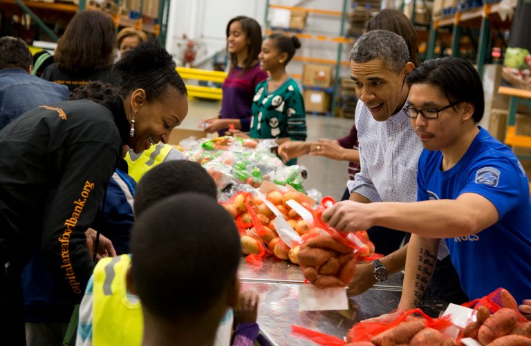 President Barack Obama participates in a Thanksgiving service project by handing out food at the Capital Area Food Bank on Wednesday, Nov. 27, 2013 in Washington. The Capital Area Food Bank distributes 30 million pounds of food annually. (AP Photo/ Evan Vucci)